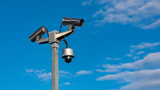 depicting a tall metal beam on which three security cameras are mounted.