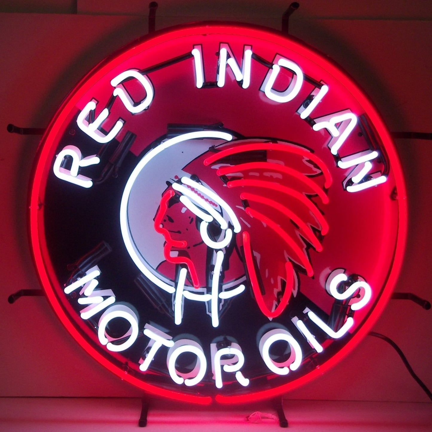 "Red Indian Motor Oils" in white neon surrounding neon depiction of the brand's logo. Neon set on top of red and black background.